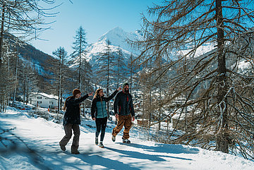 Drei Personen laufen durch Schnee