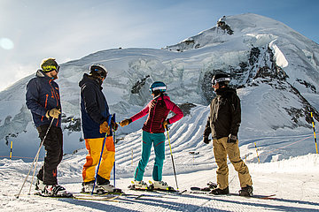 Vier skiërs op de piste tijdens hun wintervakantie in het vakantiegebied Saas-Fee/Saastal